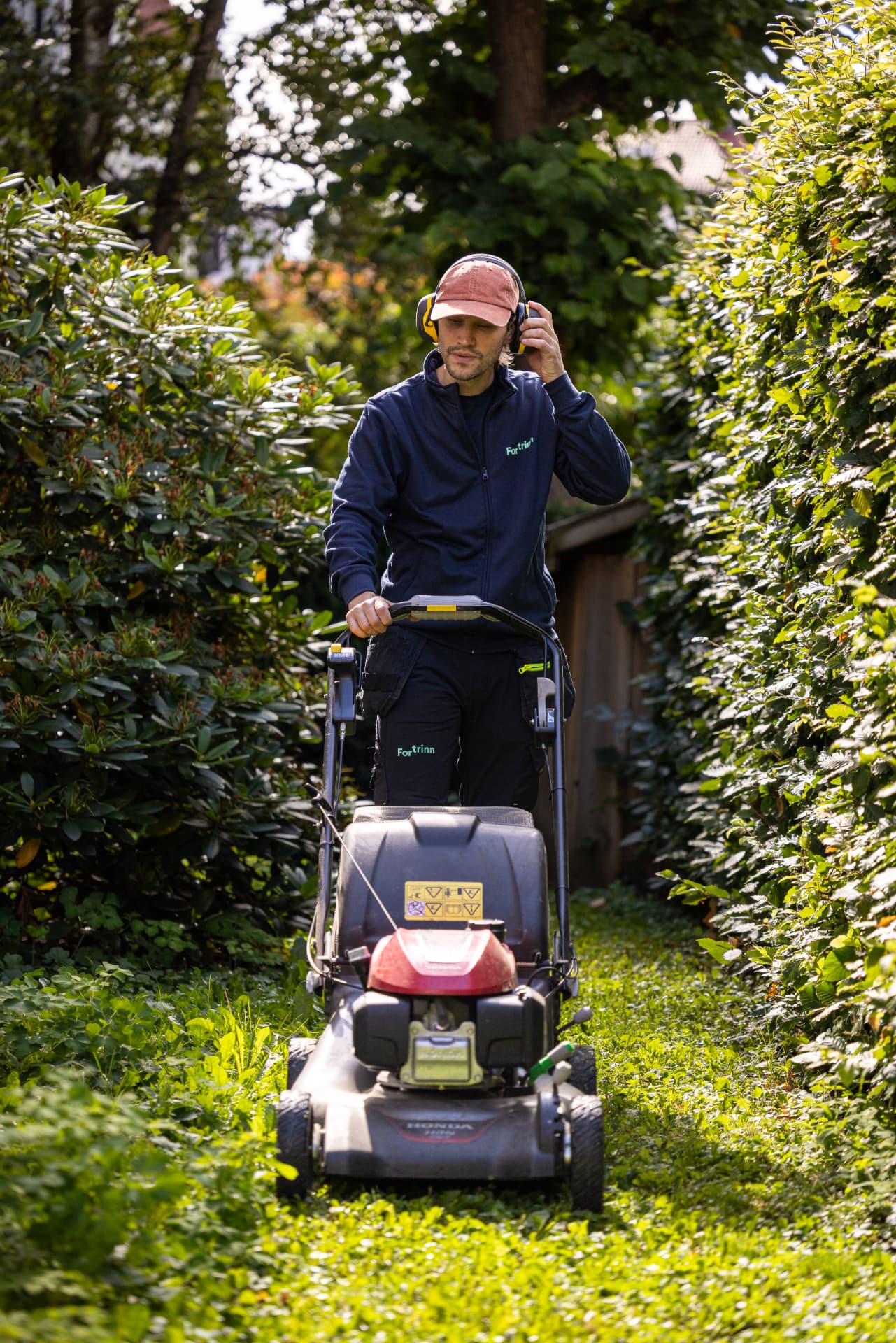 Ansatt hos Fortrinn klipper plenen i et borettslag